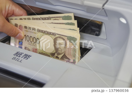 ATMからお金を引き出す男性の手元 137960036