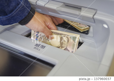 ATMからお金を引き出す男性の手元 137960037