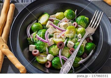 Mediterranean brussels sprouts salad with feta cheese, olives and red onion in black bowl  137960331