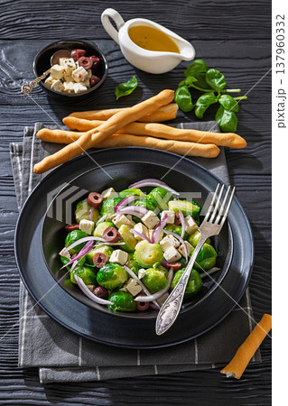 Mediterranean brussels sprouts salad with feta cheese, olives and red onion in black bowl  137960332