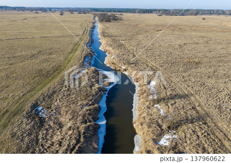Narew river winding through dry fields with melting ice 137960622