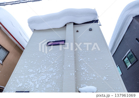 雪国の生活:吹雪の後の住宅地、屋根には大きな雪庇、外壁には吹き付けられた雪がたくさんついている 雪国の生活:吹雪の後の住宅地、屋根には大きな雪庇、外壁には吹き付けられた雪がたくさんついている 137961069