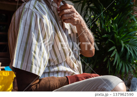 Close up of senior man holding chest while sitting outdoors suggesting discomfort health risk aging lifestyle and medical concern concept Close up of senior man holding chest while sitting outdoors suggesting discomfort health risk aging lifestyle and medical concern concept 137962590