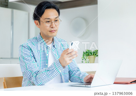 リビングで仕事するミドル男性 137963006