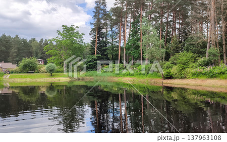 A calm pond sits in the middle of a green spring park. A feeling of balance and quiet relaxation. 137963108