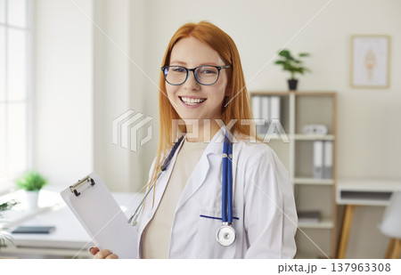Young smiling doctor, beautiful red-haired girl medical health professional, healthcare assistant Young smiling doctor, beautiful red-haired girl medical health professional, healthcare assistant 137963308