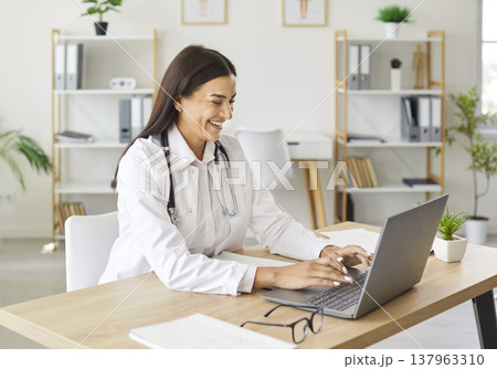 Happy Female Doctor Or Nurse Working Online With Laptop In Hospital Office 137963310