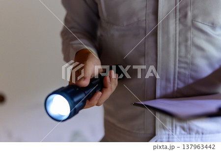 作業着の男性が懐中電灯と書類を持って点検する 137963442