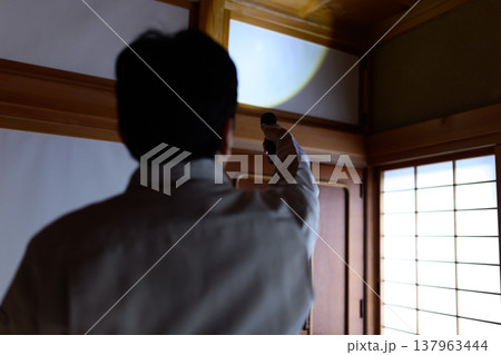 暗い和室で天井を照らす作業員 137963444
