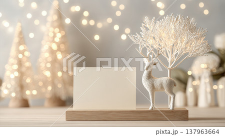 Minimalist holiday scene featuring a white paper card on a wooden base next to a deer statue. Soft bokeh lights and golden tones create a sophisticated winter atmosphere for card presentations 137963664