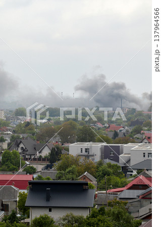 Thick black smoke rising over a residential area after an explosion or fire. Concept of war in Ukraine, missile strike consequences, and urban destruction. Aerial view of a city under attack 137964566