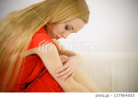 Sad elegant woman sitting on sofa Sad elegant woman sitting on sofa 137964883