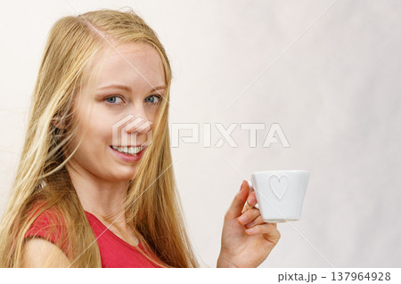 Blonde girl blowing hair holds coffee cup Blonde girl blowing hair holds coffee cup 137964928