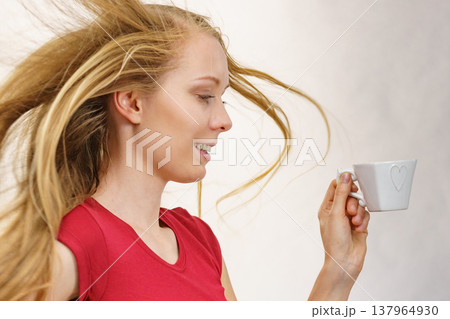 Blonde girl blowing hair holds coffee cup Blonde girl blowing hair holds coffee cup 137964930