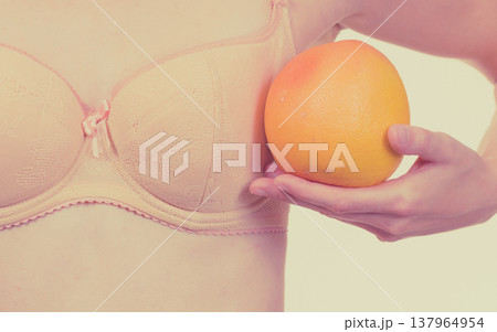 Woman small boobs holds big orange fruits Woman small boobs holds big orange fruits 137964954