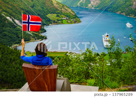 Tourist over Geirangerfjord holds norwegian flag Tourist over Geirangerfjord holds norwegian flag 137965289