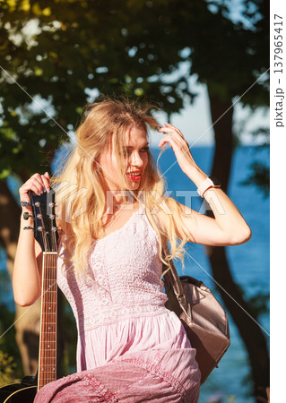 Blonde woman with acoustic guitar on seaside Blonde woman with acoustic guitar on seaside 137965417