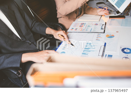 Two business people talk project strategy at office meeting room. Businessman discuss project planning with colleague at modern workplace while having conversation and advice on financial data report. 137965497