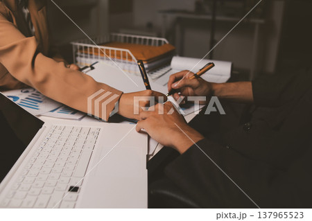 Two business people talk project strategy at office meeting room. Businessman discuss project planning with colleague at modern workplace while having conversation and advice on financial data report. 137965523