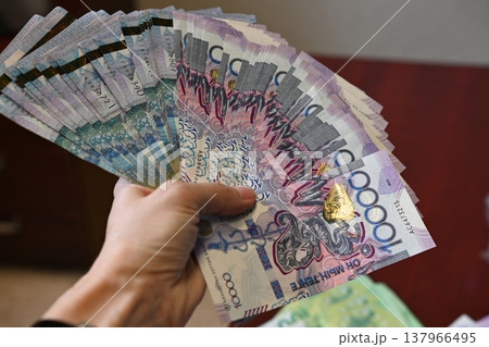 Holding a fan of colorful banknotes in hand during a financial transaction at a local market in the afternoon light 137966495