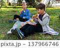 Two boys eating pizza on picnic blanket in park, outdoor lunch, friendship and summer lifestyle 137966746