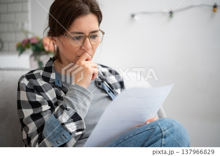 Girl In Glasses Reading Unpleasant Notice With Financial Information Girl In Glasses Reading Unpleasant Notice With Financial Information 137966829