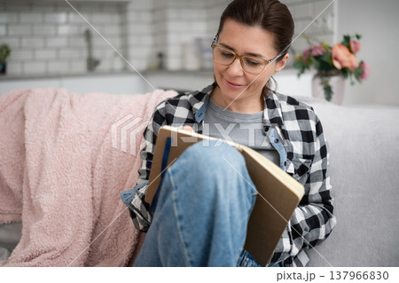 Girl In Glasses Writing Notes In A Notebook Makes A List Of Important Things To Do At Home Girl In Glasses Writing Notes In A Notebook Makes A List Of Important Things To Do At Home 137966830