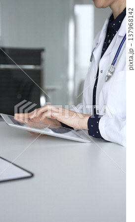 Doctor woman using digital tablet for medical consultation, female physician working with patient data in clinic. Medicine, healthcare and science concept Doctor woman using digital tablet for medical consultation, female physician working with patient data in clinic. Medicine, healthcare and science concept 137968142