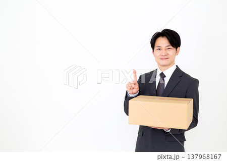 段ボールの荷物を持って人差し指を立てるミドル男性ビジネスマン 137968167