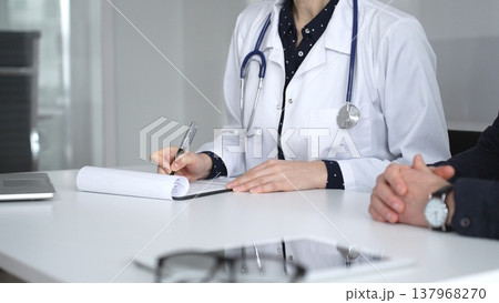 Experienced female doctor consulting patient man, providing medical advice and writing prescription during hospital appointment. Medicine, healthcare and science concept Experienced female doctor consulting patient man, providing medical advice and writing prescription during hospital appointment. Medicine, healthcare and science concept 137968270