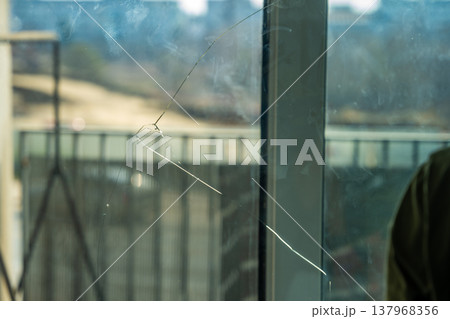 Cracked window glass with visible fracture lines in apartment. Damaged glass surface and need for repair or replacement concept. Cracked window glass with visible fracture lines in apartment. Damaged glass surface and need for repair or replacement concept. 137968356
