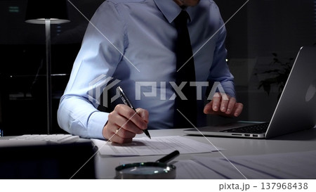 Businessman working overtime in office signing document at night, preparing contracts and finances. Audit and taxes in business 137968438