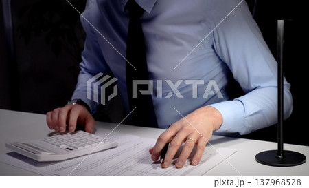 Professional businessman analyzing financial data and statistics, calculating costs, making important budget reports at office desk. Audit and taxes theme in business Professional businessman analyzing financial data and statistics, calculating costs, making important budget reports at office desk. Audit and taxes theme in business 137968528