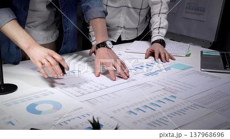 Business professionals analyzing financial data and market trends, reviewing growth charts, and developing strategic plans for company success while collaborating on paperwork 137968696