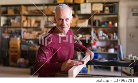 Senior man sanding wood plank creating carpentry craft Senior man sanding wood plank creating carpentry craft 137968781