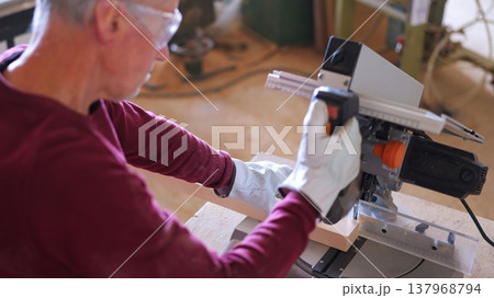 Carpenter cutting wood with miter saw wearing safety glasses Carpenter cutting wood with miter saw wearing safety glasses 137968794