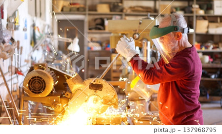 Senior metalworker cutting metal in workshop creating sparks 137968795
