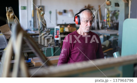 Experienced carpenter working with wood in workshop 137968796