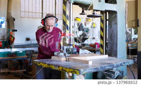 Senior carpenter cutting wood using a band saw 137968812