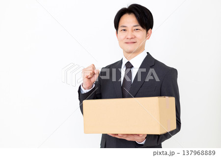 段ボールの荷物を持ってガッツポーズをするミドル男性ビジネスマン 段ボールの荷物を持ってガッツポーズをするミドル男性ビジネスマン 137968889