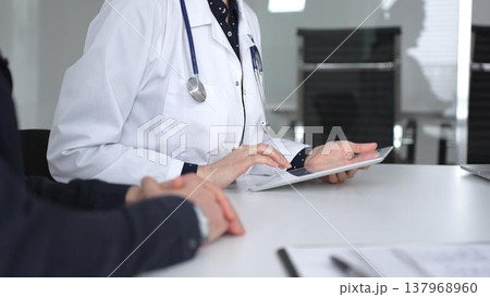 Female doctor consulting patient man using digital tablet, discussing medical records in modern clinic office, healthcare technology. Medicine, healthcare and science concept Female doctor consulting patient man using digital tablet, discussing medical records in modern clinic office, healthcare technology. Medicine, healthcare and science concept 137968960