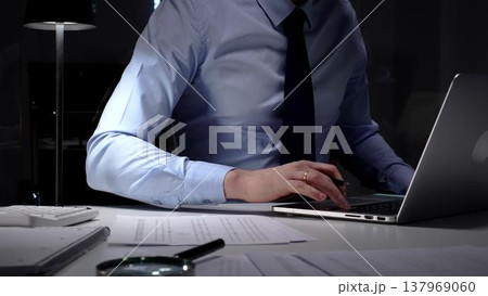 Businessman working overtime in office signing document at night, preparing contracts and finances. Audit and taxes in business Businessman working overtime in office signing document at night, preparing contracts and finances. Audit and taxes in business 137969060