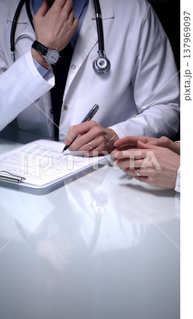 Doctor explaining medical diagnosis to a patient during a consultation, providing healthcare advice and discussing treatment options in a professional clinic setting, emphasizing health and wellness 137969097