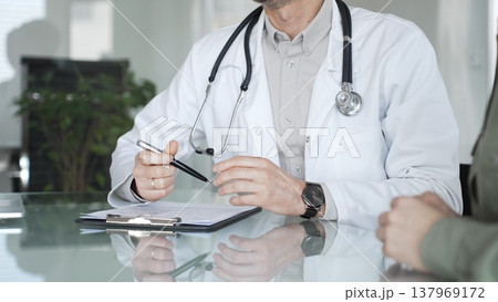 Doctor and patient discussing medical diagnosis, providing healthcare advice during consultation in clinic office. Medicine, health care and science concept Doctor and patient discussing medical diagnosis, providing healthcare advice during consultation in clinic office. Medicine, health care and science concept 137969172