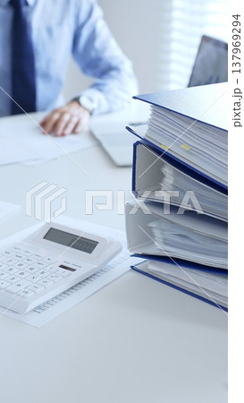 Business partners reviewing financial documents charts and diagrams , working collaboratively at white desk in office. Audit and taxes in business Business partners reviewing financial documents charts and diagrams , working collaboratively at white desk in office. Audit and taxes in business 137969294