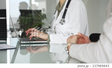 Doctor woman typing on laptop during medical consultation with patient, discussing healthcare technology and modern diagnostics. Medicine, health care and science concept Doctor woman typing on laptop during medical consultation with patient, discussing healthcare technology and modern diagnostics. Medicine, health care and science concept 137969843
