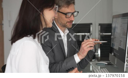 Business professionals collaborating and discussing information on a computer screen during a meeting in an office setting, actively engaging in teamwork and strategic planning. Businesspeople concept Business professionals collaborating and discussing information on a computer screen during a meeting in an office setting, actively engaging in teamwork and strategic planning. Businesspeople concept 137970158