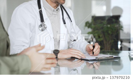 Doctor man writing prescription during patient consultation in clinic, providing medical advice and healthcare service. Medicine, health care and science concept 137970210
