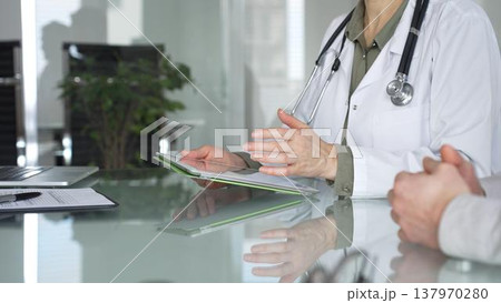 Female doctor holding a digital tablet while discussing medical information with patient during a healthcare consultation, close-up. Medicine, health care and science concept Female doctor holding a digital tablet while discussing medical information with patient during a healthcare consultation, close-up. Medicine, health care and science concept 137970280