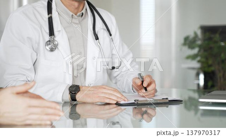 Doctor man writing prescription during patient consultation in clinic, providing medical advice and healthcare service. Medicine, health care and science concept Doctor man writing prescription during patient consultation in clinic, providing medical advice and healthcare service. Medicine, health care and science concept 137970317